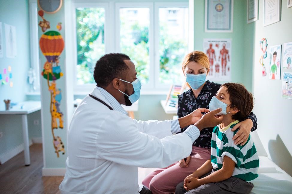 Pediatrician with child and parent, wearing masks