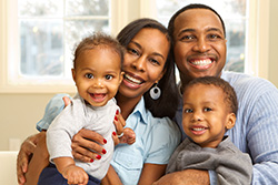 A happy and healthy African-American family at home with mother, father, and two small children
