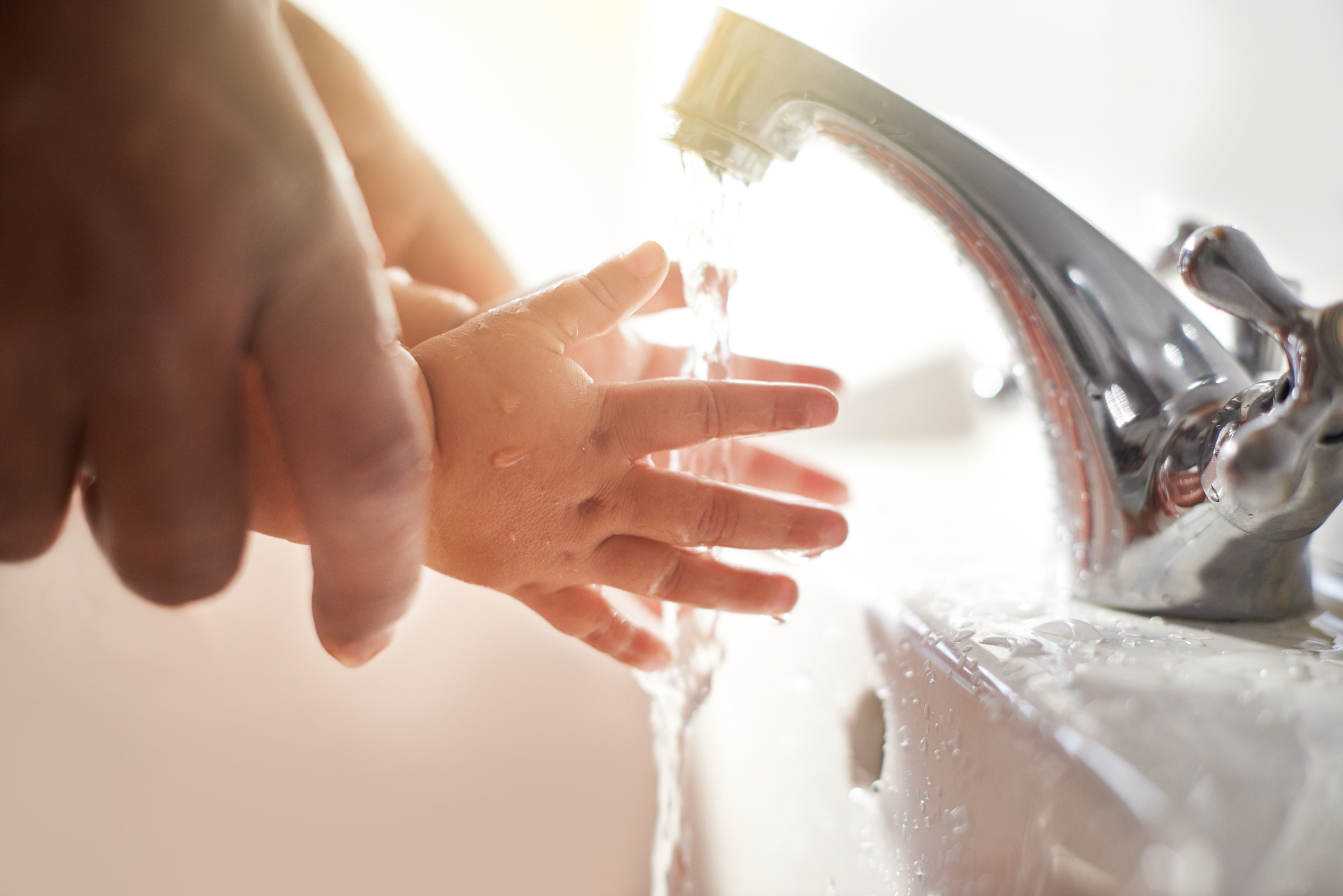 Close up of a child and adult washing hands