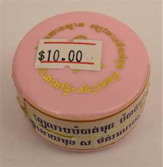 round pink container of face cream with gold lettering on the cap, a $10 price sticker, and words written in khmer on the body
