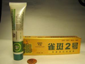 A white and green tub of face cream next to its yellow box with green lettering in chinese