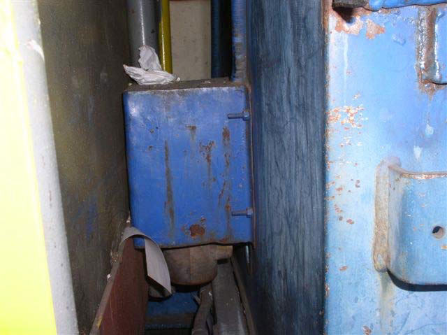 A blue metal box is bolted to the side of a larger blue metal structure.