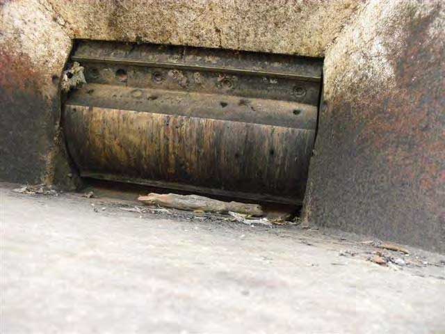 A close-up view of the inside of the chipper feeder chute shows the blades attached to the rotating drum that chip brush. There is a fragment of wood inside.