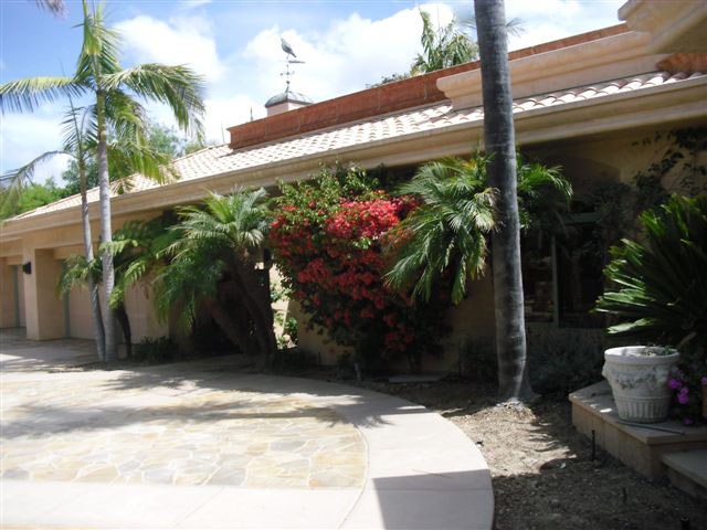 Front entryway of home where worker fatality occurred. Home is stucco and one story high with palm trees and flowers planted near entry.