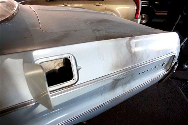 Left rear quarter panel of car with close-up of open fuel filler door and burn marks on paint between open gas cap and Impala lettering and logo near rear bumper.