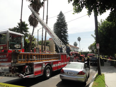 The emergency response to the incident with a ladder-equipped fire truck in the middle of the street.