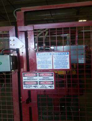 Safety signs in English and Spanish are posted on the gate into the restricted area.