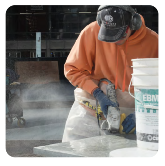 Worker with hearing protection sanding stone  countertop outdoors