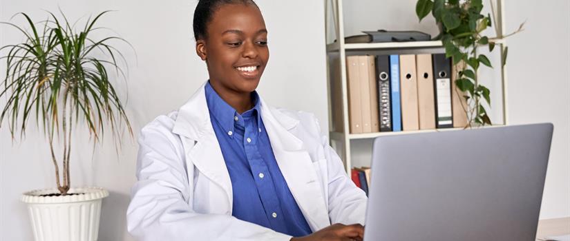 Smiling doctor looks down at her laptop screen