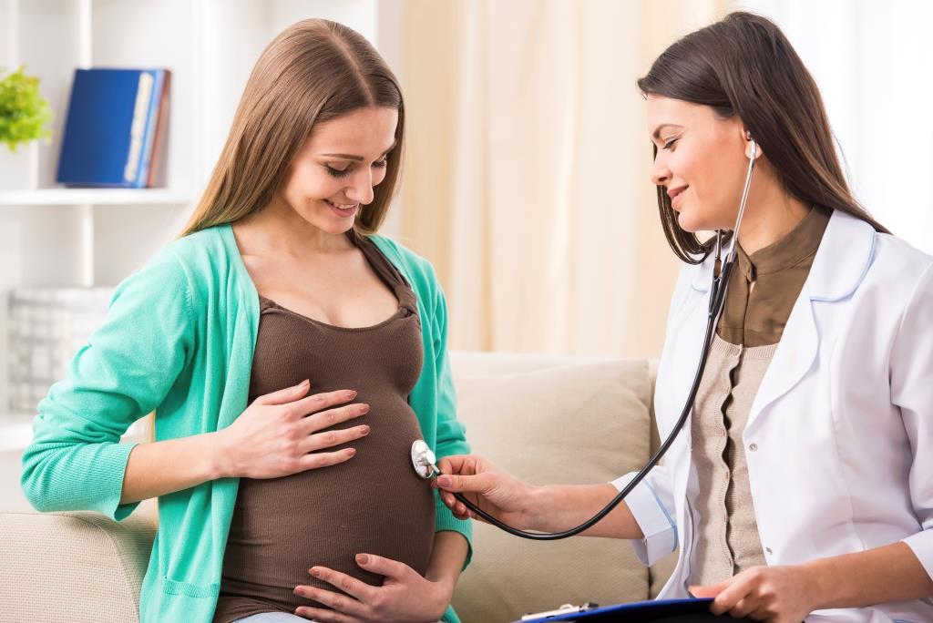 Young female doctor examing pregnant women in her third trimester