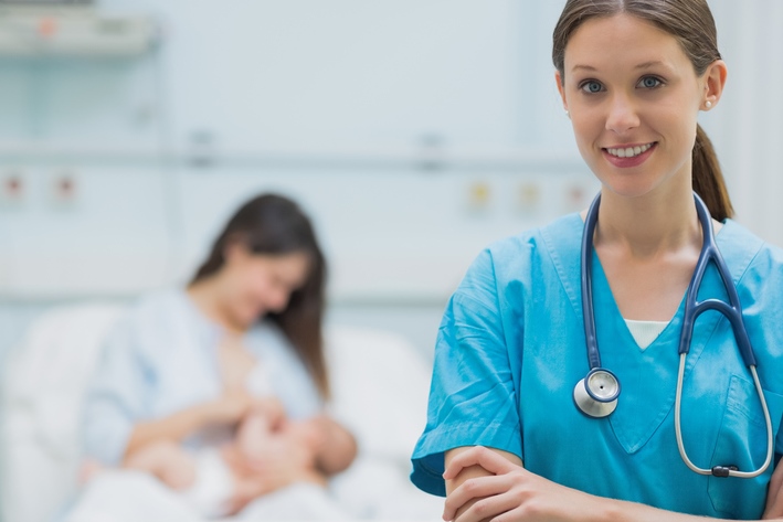 Close-up of health professional with  mother breastfeeding infant lovingly in background