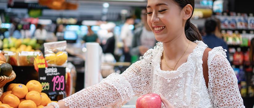 Young Asian woman shopping for fresh organic fruits in supermarket : Stock Photo