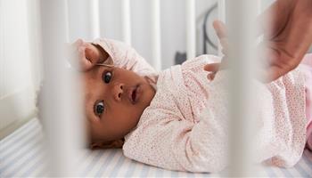 Newborn infant sleeping on back in crib