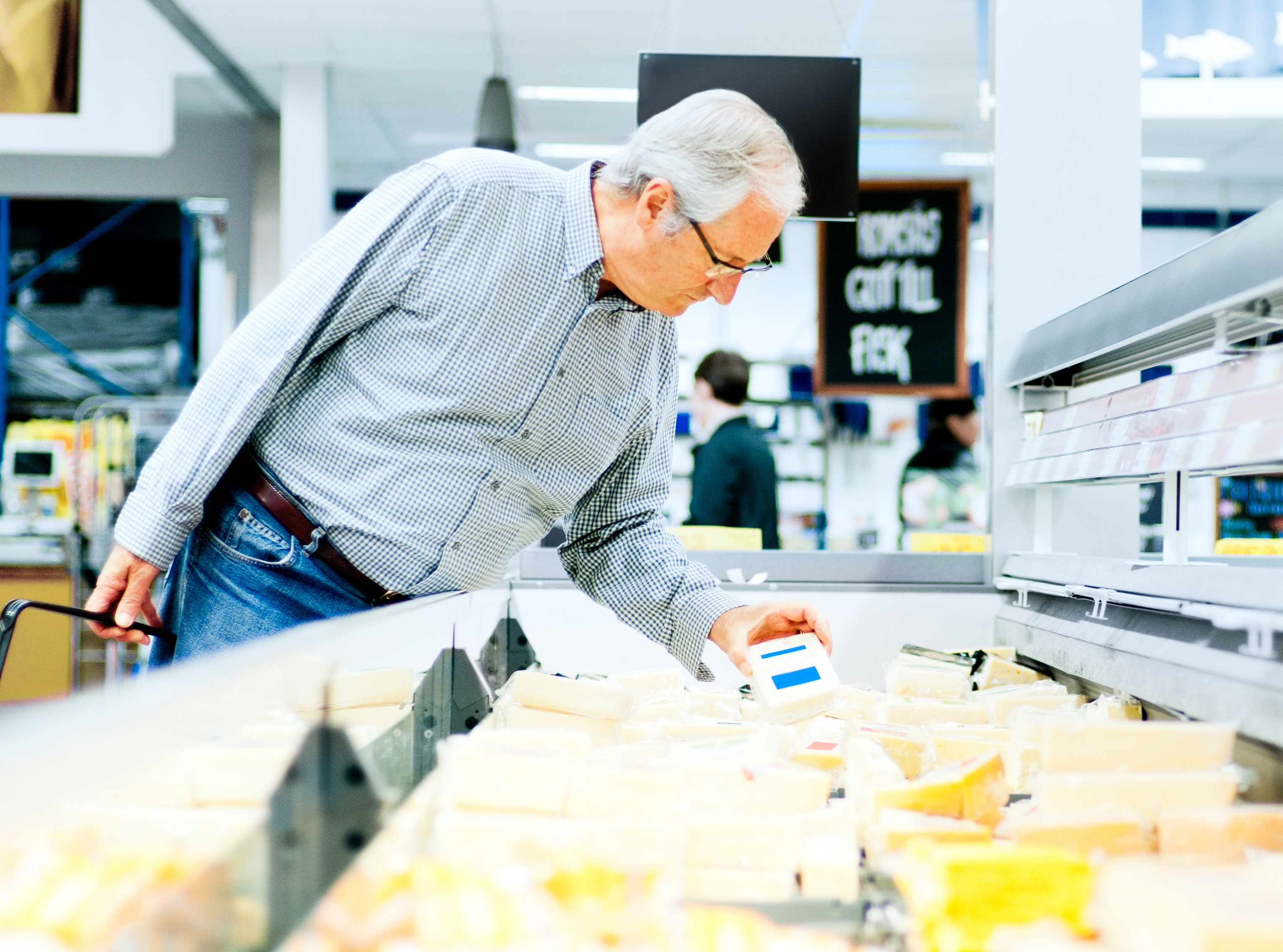 Man reading cheese label at a grocery store