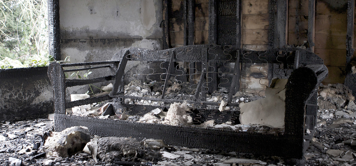 Couch burned by fire and covered in ash